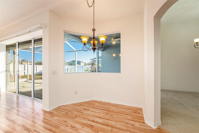 unfurnished dining area with a chandelier and wood-type flooring