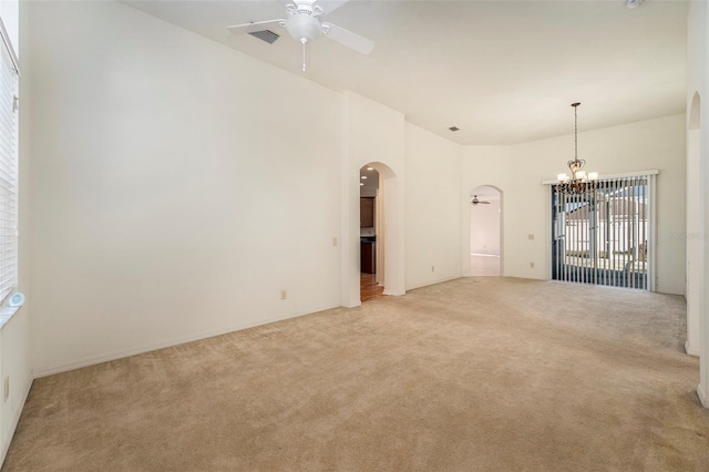 carpeted empty room featuring ceiling fan with notable chandelier