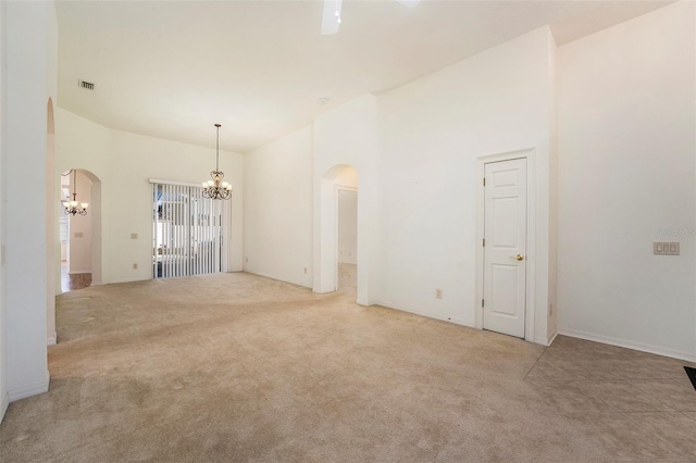 empty room featuring a high ceiling, light colored carpet, and an inviting chandelier