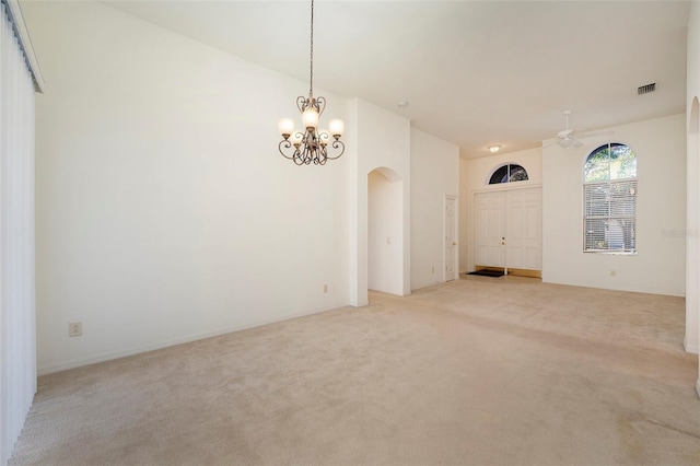 carpeted empty room with ceiling fan with notable chandelier