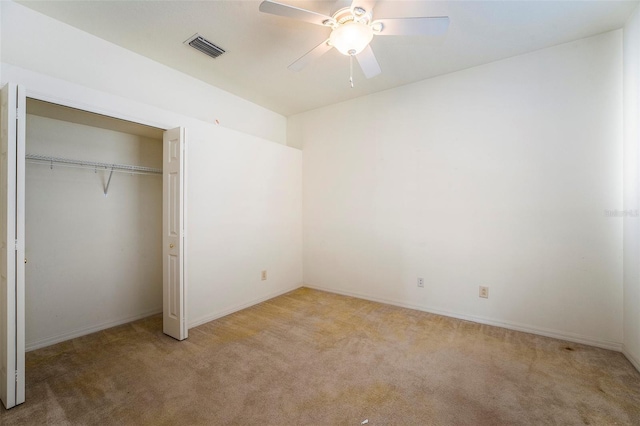 unfurnished bedroom featuring ceiling fan, a closet, and light colored carpet