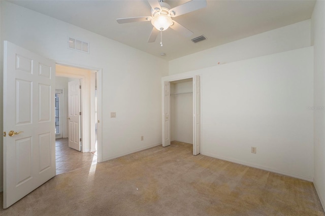 unfurnished bedroom with ceiling fan, light carpet, and a closet