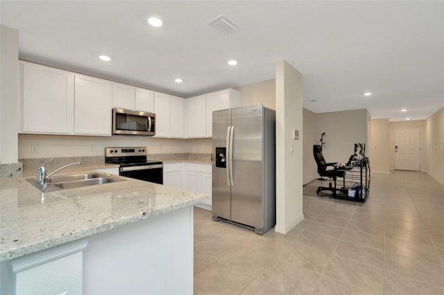 kitchen with light stone counters, stainless steel appliances, sink, white cabinets, and light tile patterned flooring