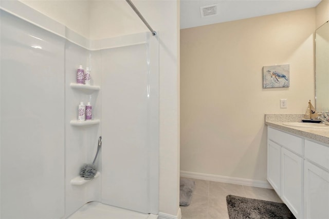 bathroom with a shower, tile patterned flooring, and vanity