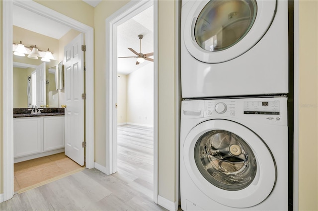 washroom featuring sink, light hardwood / wood-style flooring, stacked washer / dryer, and ceiling fan