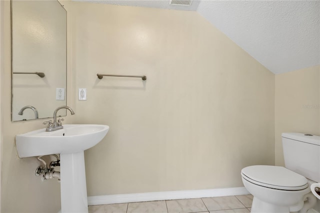 bathroom featuring tile patterned floors, toilet, lofted ceiling, and a textured ceiling