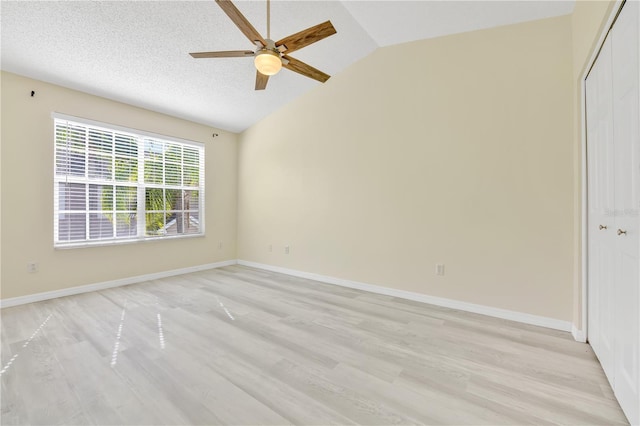 empty room with ceiling fan, light wood-type flooring, a textured ceiling, and vaulted ceiling