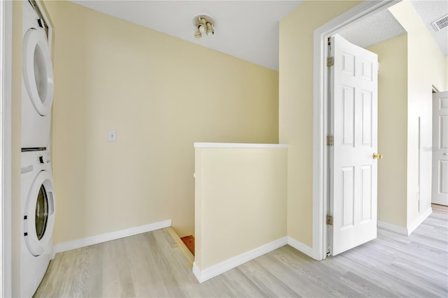 washroom featuring stacked washer / dryer and light hardwood / wood-style flooring