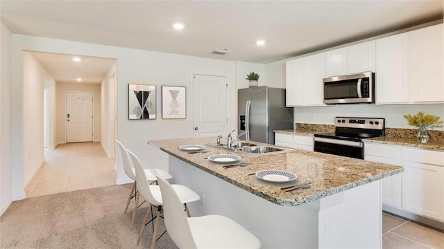 kitchen with sink, stainless steel appliances, a kitchen bar, a kitchen island with sink, and white cabinets