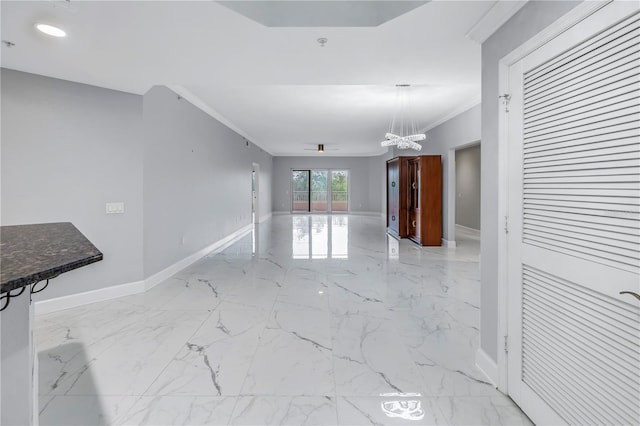 unfurnished living room featuring ornamental molding and an inviting chandelier