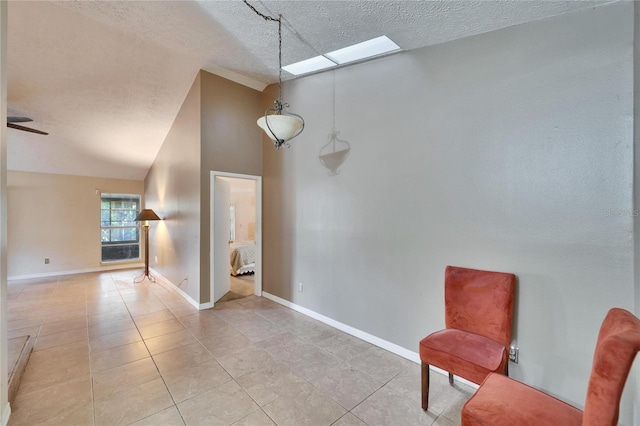 interior space featuring lofted ceiling with skylight, a textured ceiling, and light tile patterned flooring