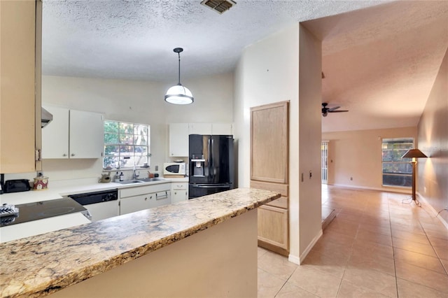 kitchen with white cabinetry, black fridge, sink, and decorative light fixtures