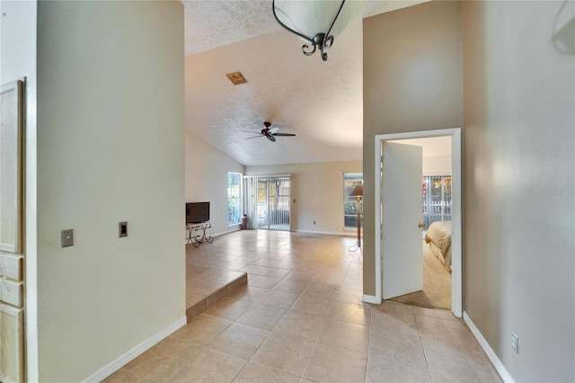 hall featuring light tile patterned floors, vaulted ceiling, and a textured ceiling