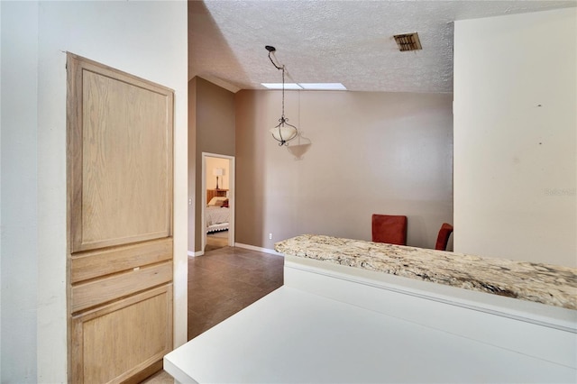 bedroom with vaulted ceiling, dark tile patterned flooring, and a textured ceiling