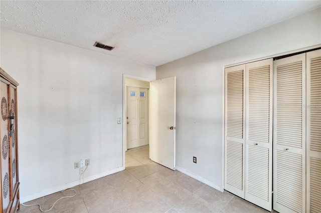 unfurnished bedroom featuring light tile patterned floors, a closet, and a textured ceiling