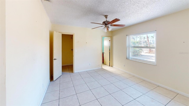 tiled spare room featuring a textured ceiling and ceiling fan