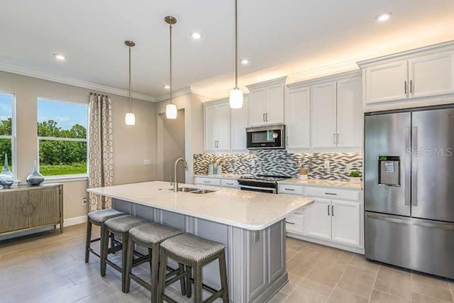 kitchen with white cabinets, appliances with stainless steel finishes, a kitchen island with sink, and pendant lighting