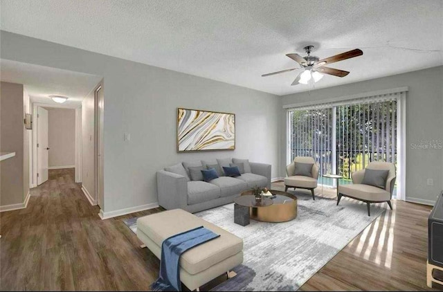 living room with a textured ceiling, ceiling fan, and dark wood-type flooring