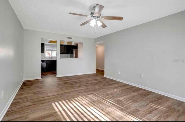 unfurnished living room featuring ceiling fan and dark hardwood / wood-style flooring