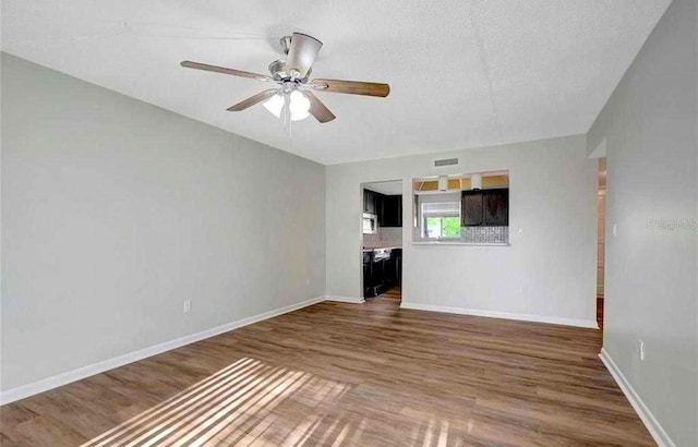 unfurnished living room featuring hardwood / wood-style floors, ceiling fan, and a textured ceiling