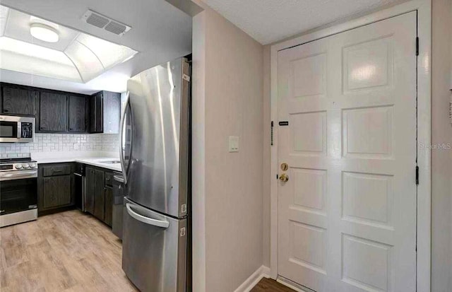 kitchen with appliances with stainless steel finishes, tasteful backsplash, and light hardwood / wood-style flooring