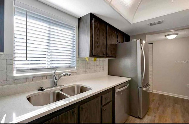 kitchen with backsplash, sink, stainless steel dishwasher, light wood-type flooring, and dark brown cabinets