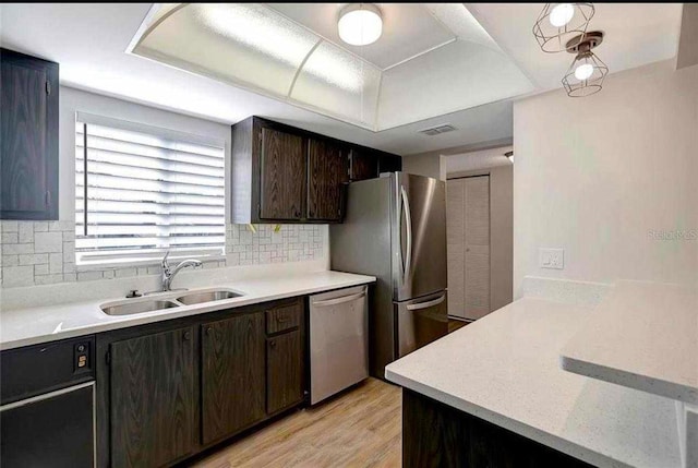 kitchen with backsplash, sink, light hardwood / wood-style flooring, appliances with stainless steel finishes, and dark brown cabinetry