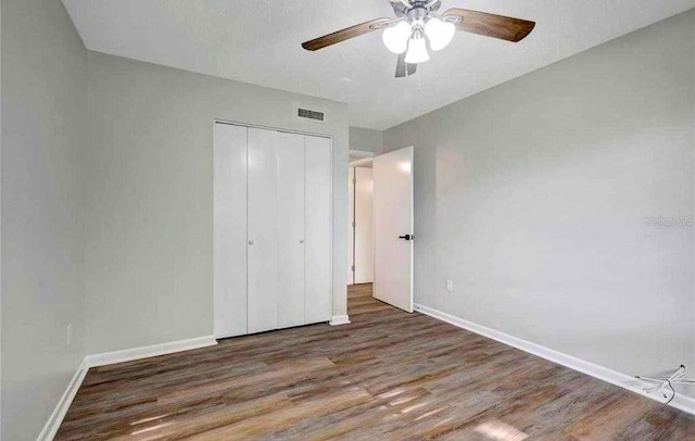 unfurnished bedroom featuring a closet, ceiling fan, and dark wood-type flooring