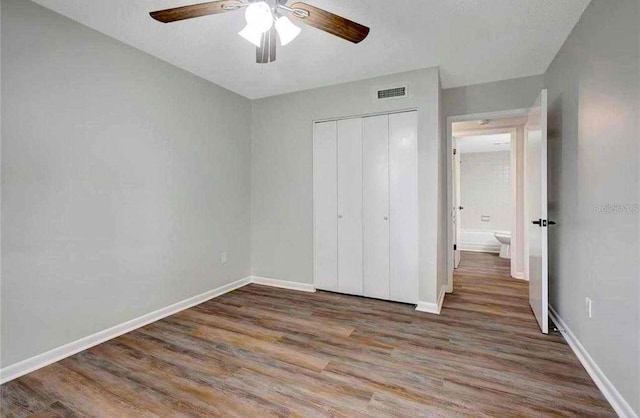 unfurnished bedroom with ceiling fan, dark wood-type flooring, and a closet