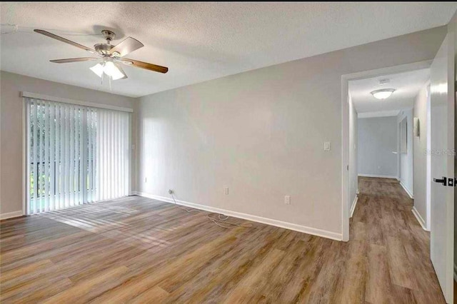 empty room with ceiling fan, light wood-type flooring, and a textured ceiling