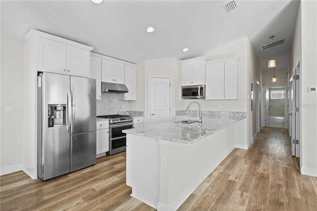 kitchen featuring sink, light stone counters, kitchen peninsula, white cabinets, and appliances with stainless steel finishes