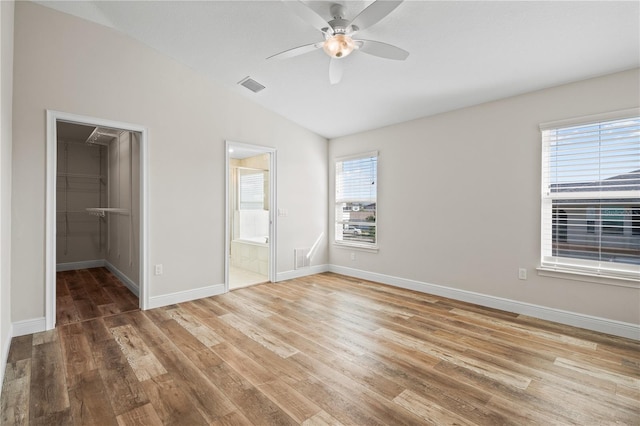 unfurnished bedroom with vaulted ceiling, a spacious closet, a closet, and ceiling fan