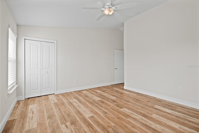 unfurnished bedroom featuring ceiling fan, a closet, light hardwood / wood-style floors, and vaulted ceiling