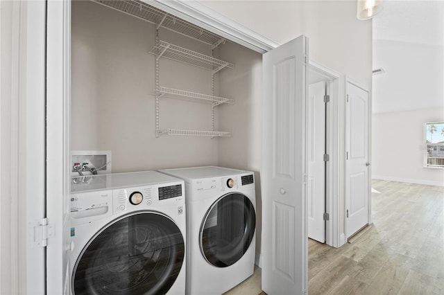 clothes washing area featuring washing machine and dryer and light wood-type flooring