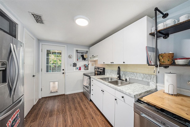 kitchen featuring sink, dark wood-type flooring, appliances with stainless steel finishes, backsplash, and white cabinets