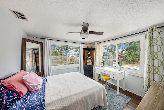 bedroom featuring ceiling fan, dark hardwood / wood-style flooring, and a textured ceiling