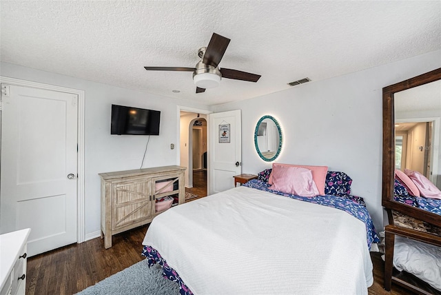 bedroom featuring dark wood-type flooring, a textured ceiling, and ceiling fan