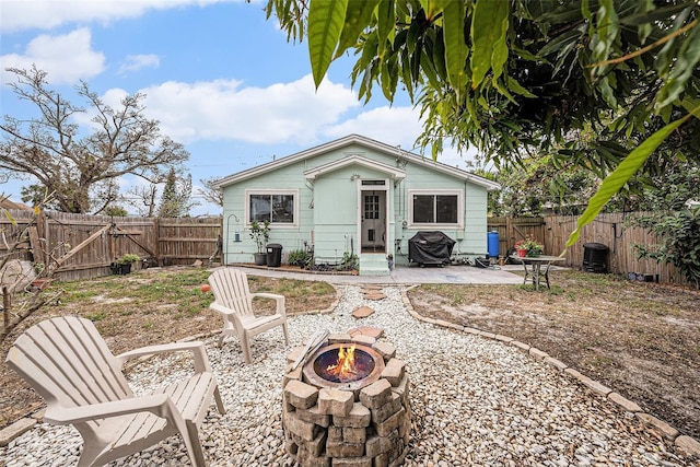 rear view of property featuring a fire pit and a patio