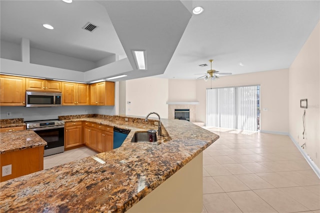 kitchen featuring dark stone counters, sink, ceiling fan, kitchen peninsula, and stainless steel appliances