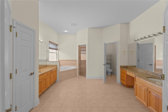 bathroom with tiled bath, tile patterned flooring, vanity, and a textured ceiling