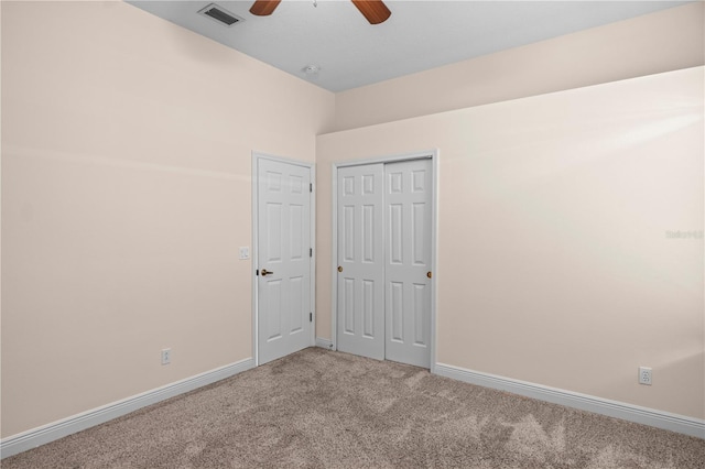 carpeted spare room with visible vents, baseboards, and ceiling fan