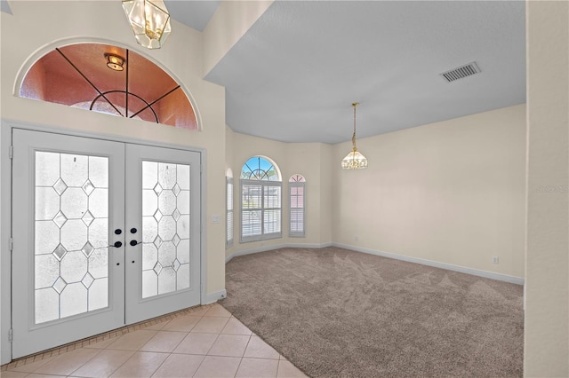 carpeted foyer entrance featuring tile patterned flooring, visible vents, baseboards, french doors, and an inviting chandelier