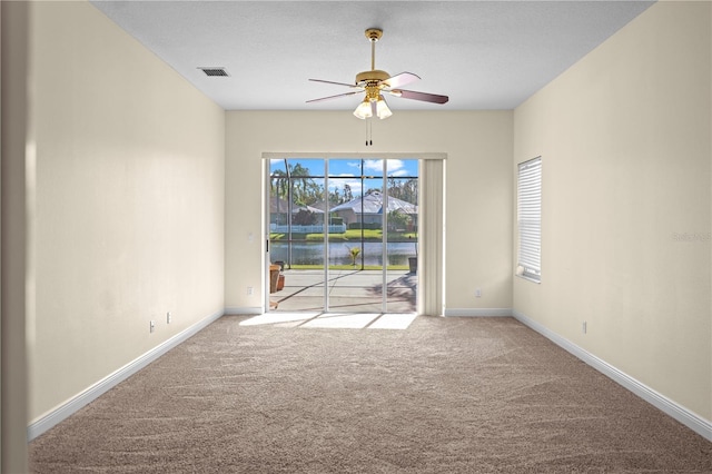 carpeted empty room featuring visible vents, ceiling fan, and baseboards