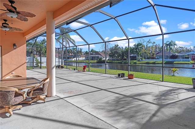 view of patio / terrace with a lanai, a ceiling fan, a water view, and a residential view