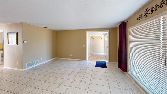 empty room with light tile patterned floors and a textured ceiling