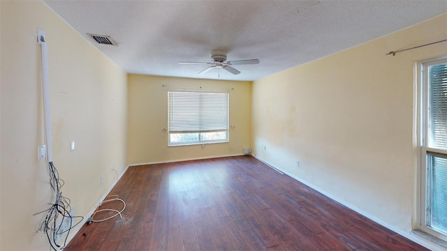 spare room with dark hardwood / wood-style floors, ceiling fan, plenty of natural light, and a textured ceiling