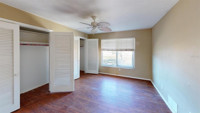 unfurnished bedroom with a textured ceiling, dark hardwood / wood-style flooring, and ceiling fan