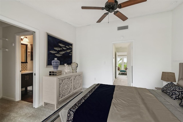 bedroom with ceiling fan, visible vents, connected bathroom, and light colored carpet