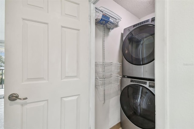 clothes washing area with stacked washer and dryer and a textured ceiling