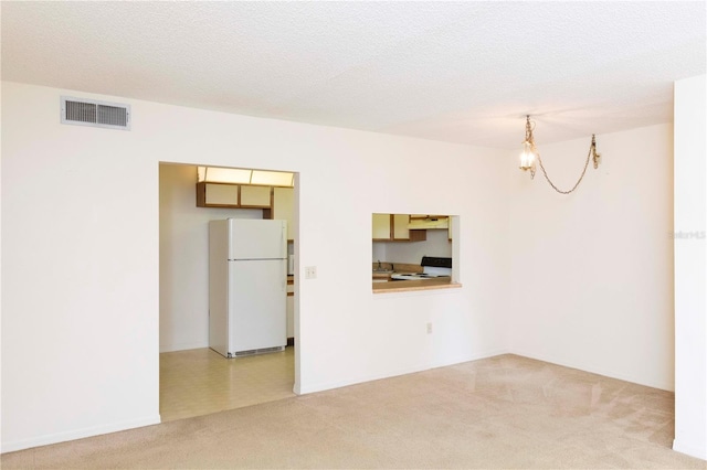 empty room with a chandelier, a textured ceiling, and carpet floors